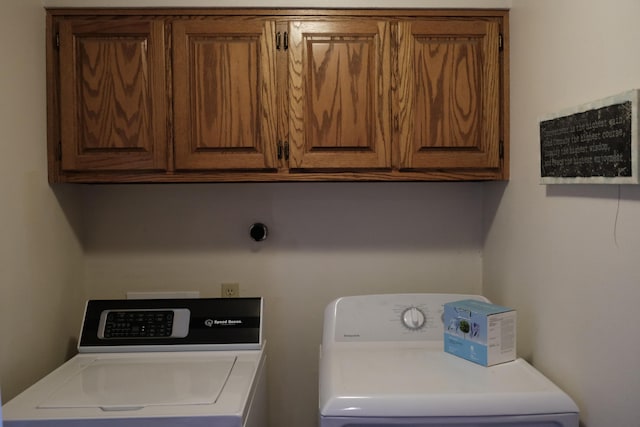 clothes washing area with washing machine and dryer and cabinet space