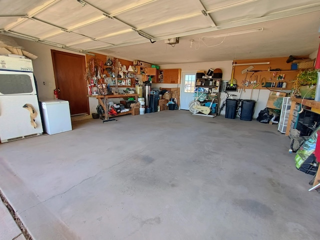 garage featuring a garage door opener, refrigerator, washer / dryer, and a workshop area