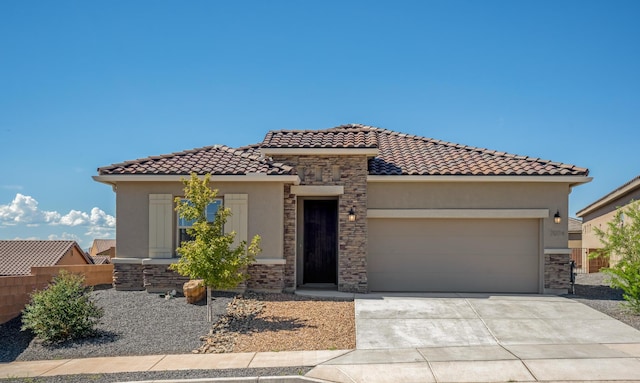 mediterranean / spanish home featuring a garage, concrete driveway, stone siding, and stucco siding