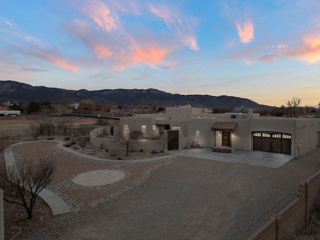 view of front of house with driveway, a garage, a mountain view, and stucco siding