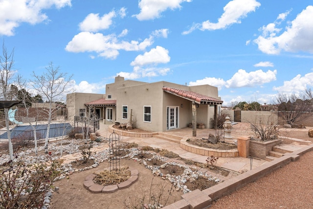 back of house with a tiled roof, a patio area, a fenced backyard, and stucco siding