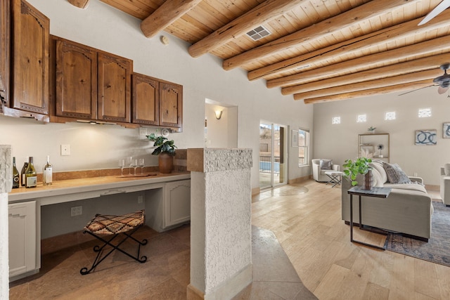 kitchen with built in study area, wooden ceiling, light wood-style flooring, open floor plan, and beam ceiling