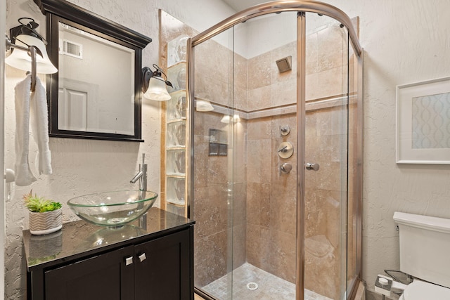 full bath featuring toilet, a stall shower, and a textured wall