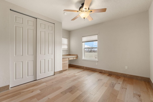 unfurnished bedroom with light wood-type flooring, baseboards, a closet, and built in study area