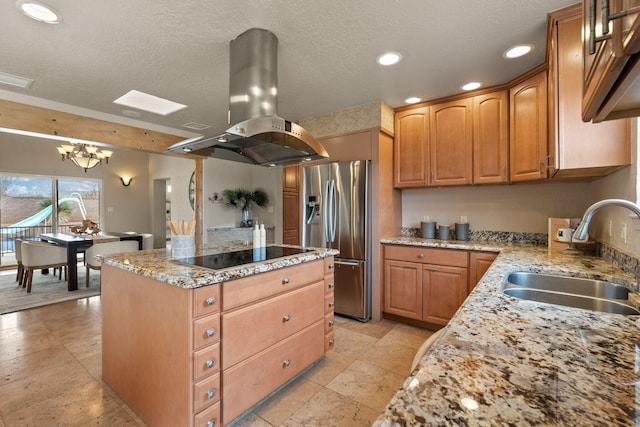 kitchen with stainless steel fridge, island range hood, a kitchen island, black electric stovetop, and a sink