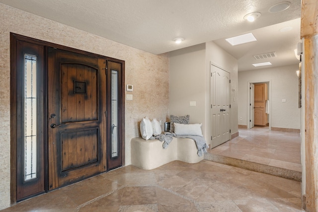 entryway with a skylight, visible vents, a textured ceiling, and baseboards