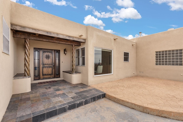 view of exterior entry featuring a patio and stucco siding