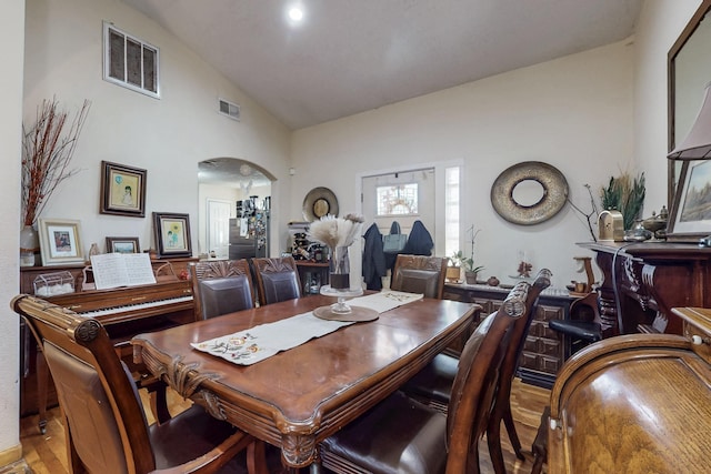 dining room with arched walkways, high vaulted ceiling, and visible vents