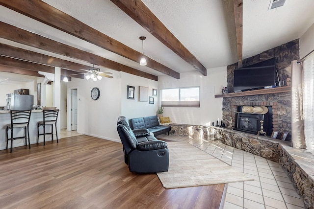 living room featuring a textured ceiling, beam ceiling, wood finished floors, and visible vents