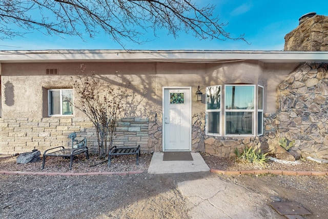 doorway to property featuring stone siding and a chimney