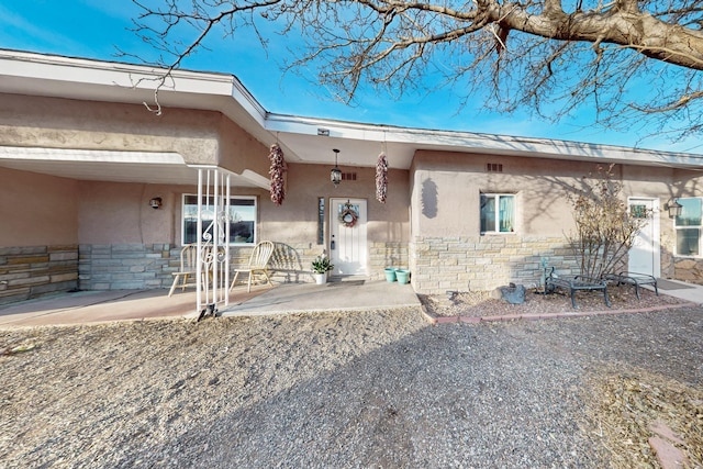 exterior space with stone siding, a patio, and stucco siding