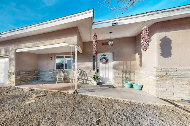 doorway to property featuring stone siding and stucco siding