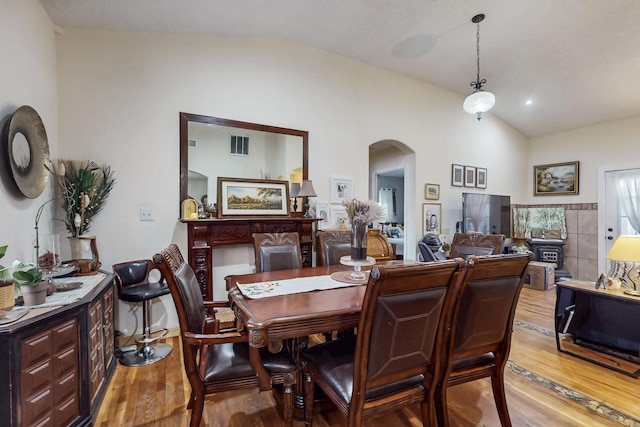 dining area with lofted ceiling, visible vents, arched walkways, and wood finished floors