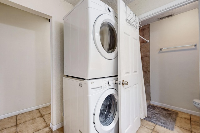 laundry room featuring laundry area, baseboards, visible vents, and stacked washing maching and dryer