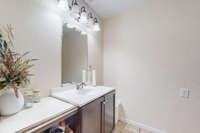 bathroom featuring a textured wall, tile patterned flooring, baseboards, and vanity