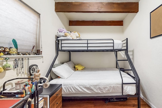 bedroom featuring baseboards, beamed ceiling, and wood finished floors