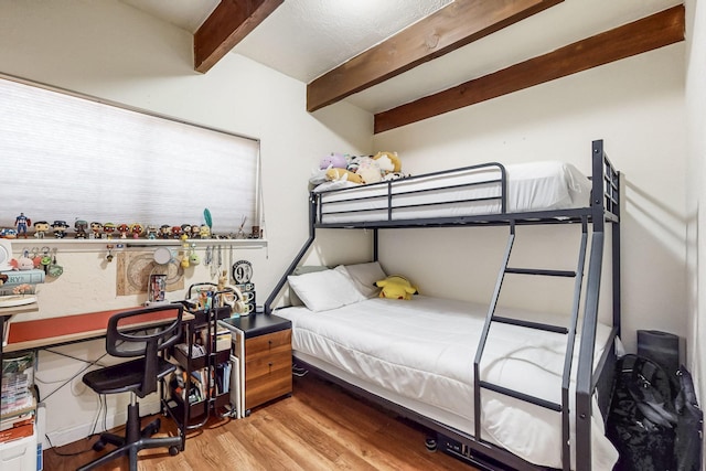 bedroom featuring beam ceiling and wood finished floors