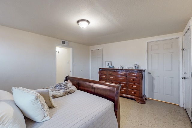 bedroom with a textured ceiling, visible vents, and a closet