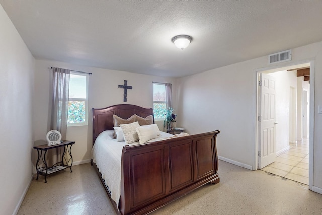 bedroom with visible vents, a textured ceiling, and baseboards