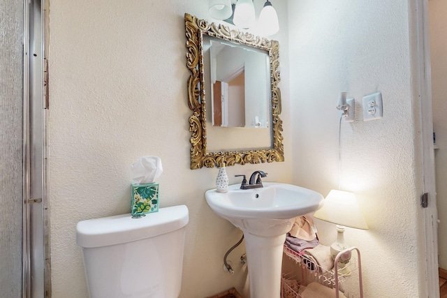 bathroom featuring a textured wall, a sink, and toilet