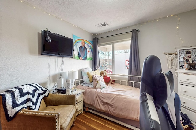 bedroom featuring a textured ceiling, wood finished floors, and visible vents