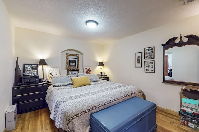 bedroom with a textured ceiling and wood finished floors