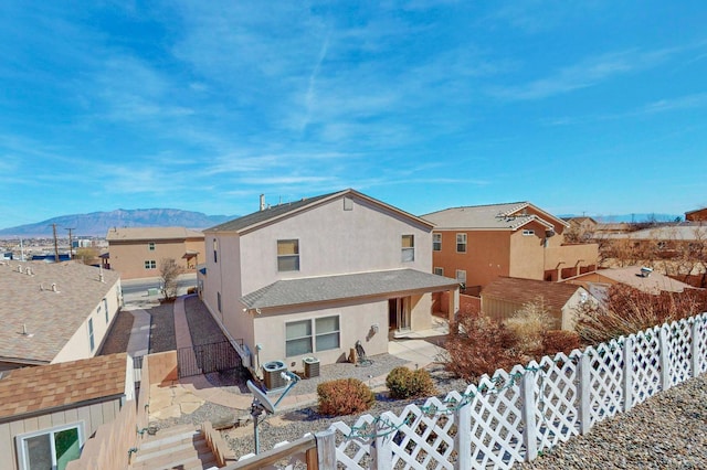 exterior space featuring a fenced backyard, a residential view, a patio area, a mountain view, and stucco siding