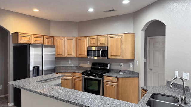 kitchen featuring arched walkways, recessed lighting, a sink, visible vents, and appliances with stainless steel finishes