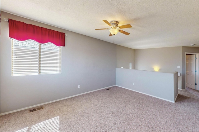 unfurnished room featuring baseboards, visible vents, a ceiling fan, carpet, and a textured ceiling