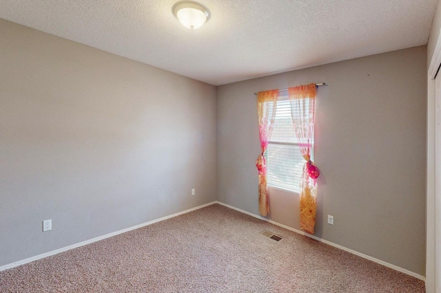 empty room featuring a textured ceiling, carpet flooring, visible vents, and baseboards