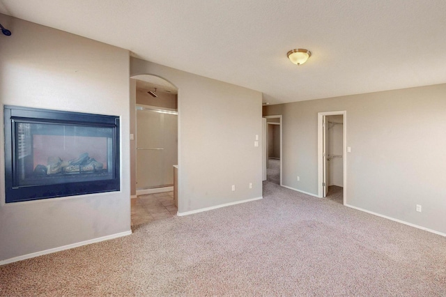 interior space with light carpet, arched walkways, and baseboards