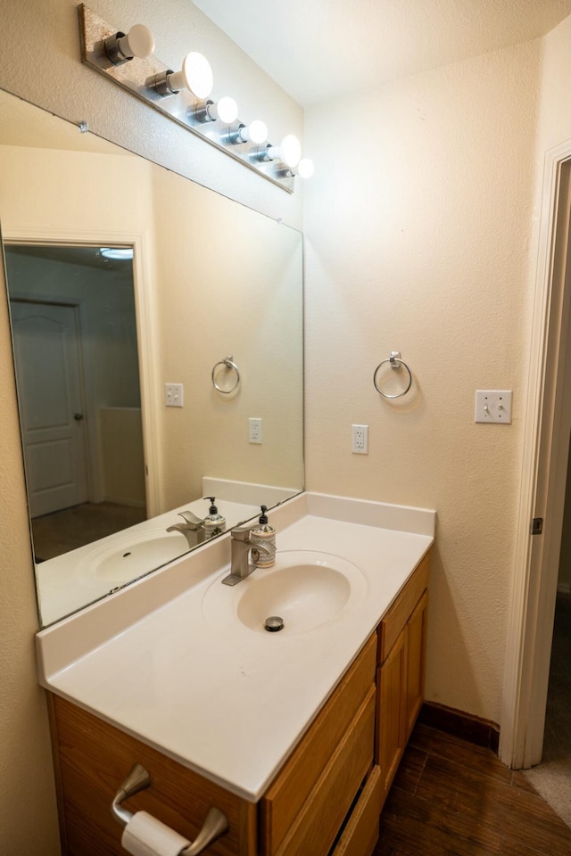 bathroom featuring baseboards, wood finished floors, and vanity