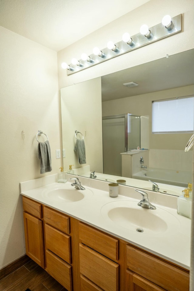 bathroom featuring double vanity, wood finished floors, a sink, and a shower stall