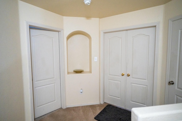 entryway featuring light carpet and baseboards