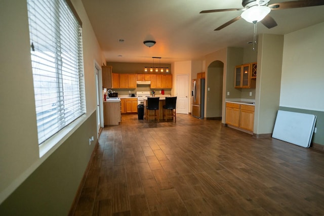 kitchen with arched walkways, light countertops, dark wood-type flooring, a sink, and stainless steel fridge with ice dispenser