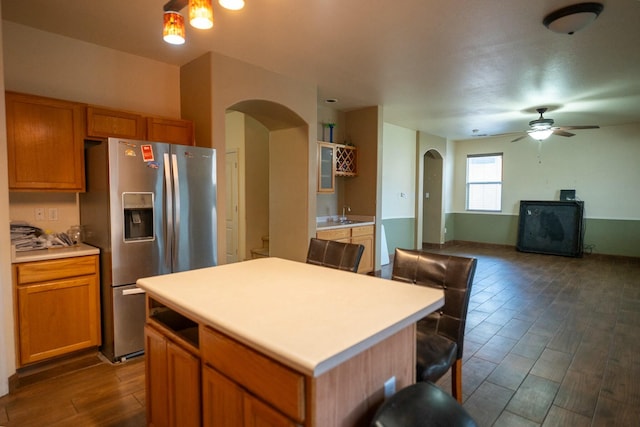 kitchen with arched walkways, light countertops, stainless steel refrigerator with ice dispenser, and dark wood finished floors