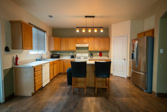 kitchen with under cabinet range hood, white appliances, a kitchen island, a sink, and visible vents