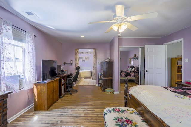 bedroom with light wood-style floors, baseboards, visible vents, and ensuite bathroom