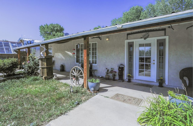 view of exterior entry featuring a patio and stucco siding