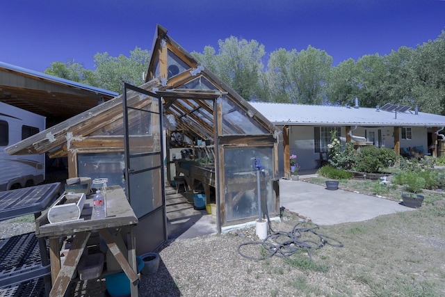 exterior space with a patio area, metal roof, an outdoor structure, and an exterior structure