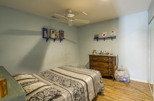 bedroom featuring a ceiling fan, visible vents, light wood-style flooring, and baseboards