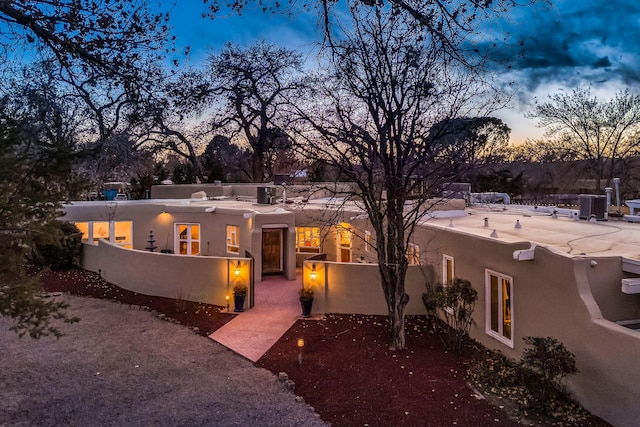 pueblo-style home featuring central AC unit