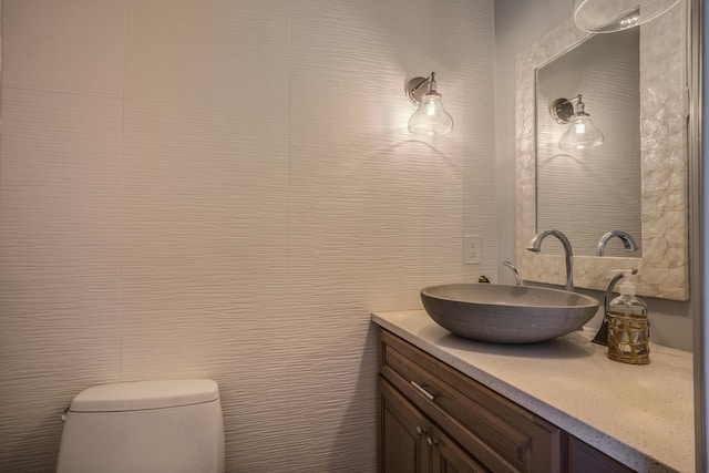 bathroom with toilet, tile walls, and vanity