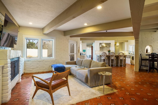 living room featuring beamed ceiling, brick wall, and a textured ceiling