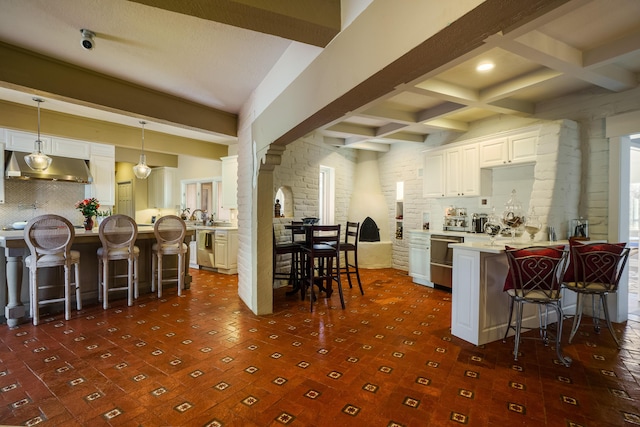 kitchen with beamed ceiling, pendant lighting, a kitchen bar, and white cabinets