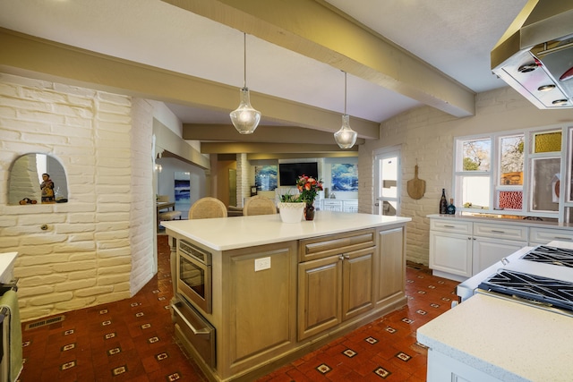 kitchen featuring stainless steel microwave, a center island, range hood, hanging light fixtures, and beam ceiling