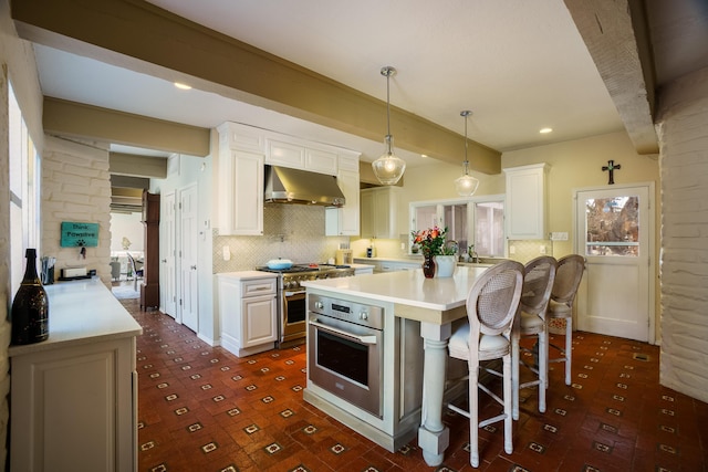 kitchen with white cabinetry, appliances with stainless steel finishes, beamed ceiling, and a breakfast bar