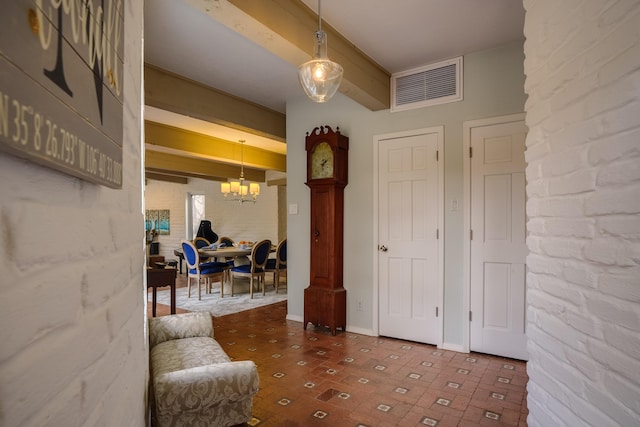 entryway featuring beam ceiling, brick wall, and a chandelier