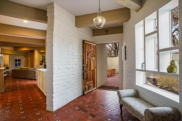 corridor featuring brick wall and beam ceiling