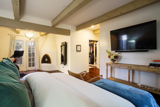 bedroom featuring wood-type flooring, a spacious closet, and beam ceiling